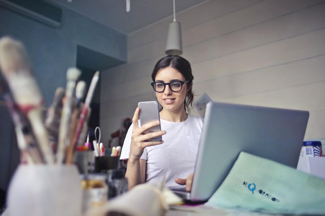 Woman at desk with mobile phone and laptop