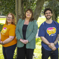 Three people facing the camera wearing Hello How Are You tshirts