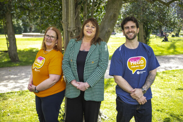 Three people facing the camera wearing Hello How Are You tshirts